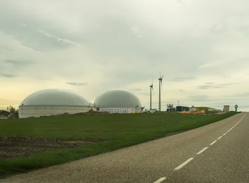 Biogasanlage mit Windräden im Hintergrund